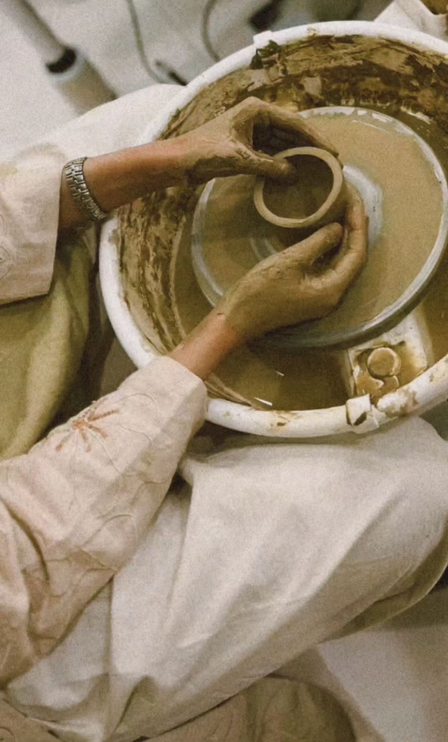 Hands centring clay on a pottery wheel during a ROA Art workshop